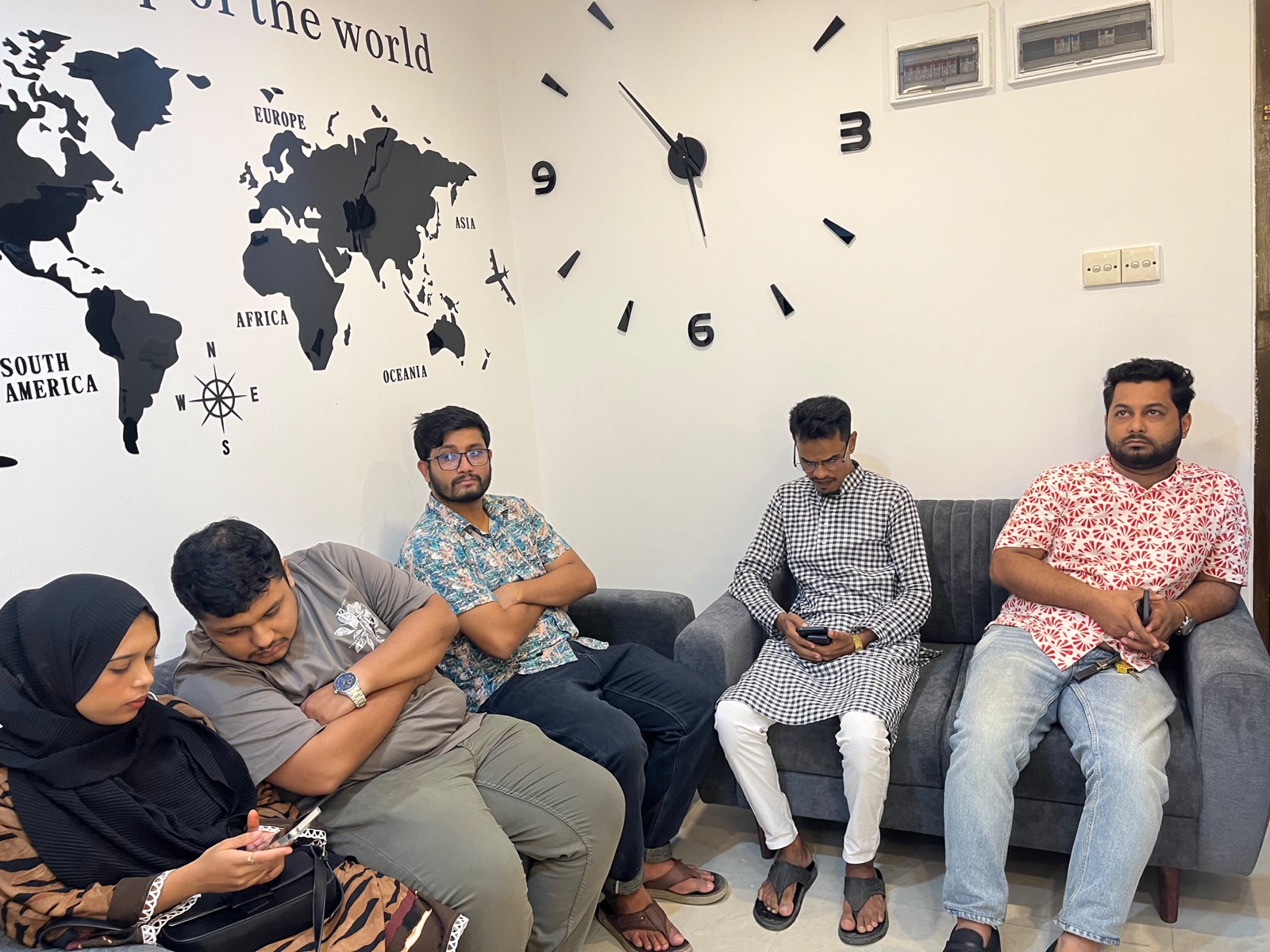 Students waiting in the lounge beneath the world map wall