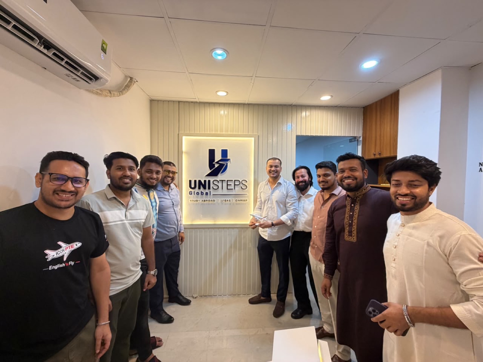 The UniSteps Global team at the office signage wall in Dhaka